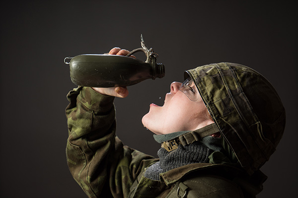 Thirsty soldier, last water droplets. Military woman, green camouflage, helmet