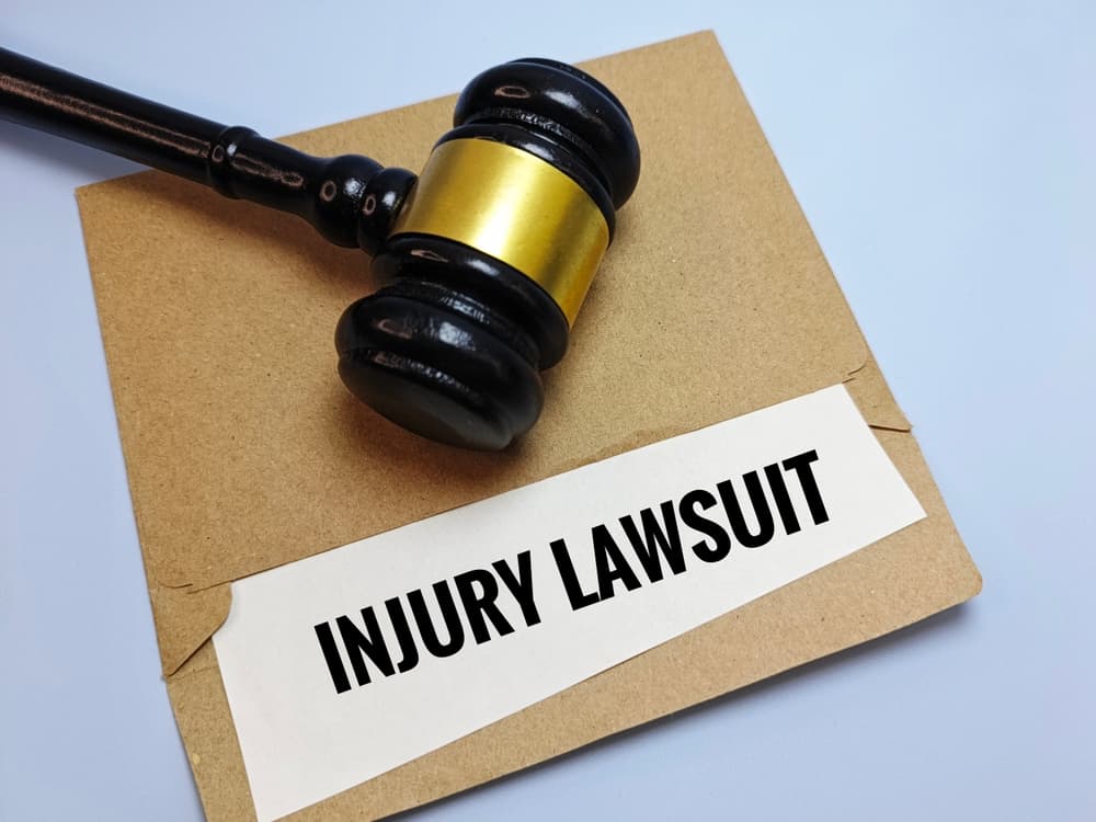 Judge&rsquo;s gavel resting on an envelope labeled Injury Lawsuit, symbolizing legal action in a personal injury case.