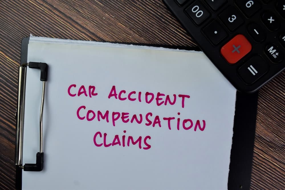 Car Accident Compensation Claims Process and Insurance Recovery Explained Car accident compensation claims concept showing a clipboard with the words car accident compensation claims, calculator, and desk workspace representing insurance or legal recovery.