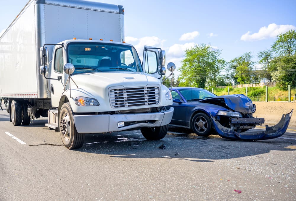 Wisconsin Truck Accident Scene Showing Commercial Truck and Car Collision Truck accident involving a commercial box truck and a damaged passenger car on a Wisconsin roadway, showing severe front-end collision damage.